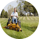 A man using a riding lawnmower to cut grass